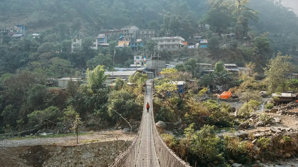 Aerial view of a high suspension bridge over a river gorge on the Manaslu region